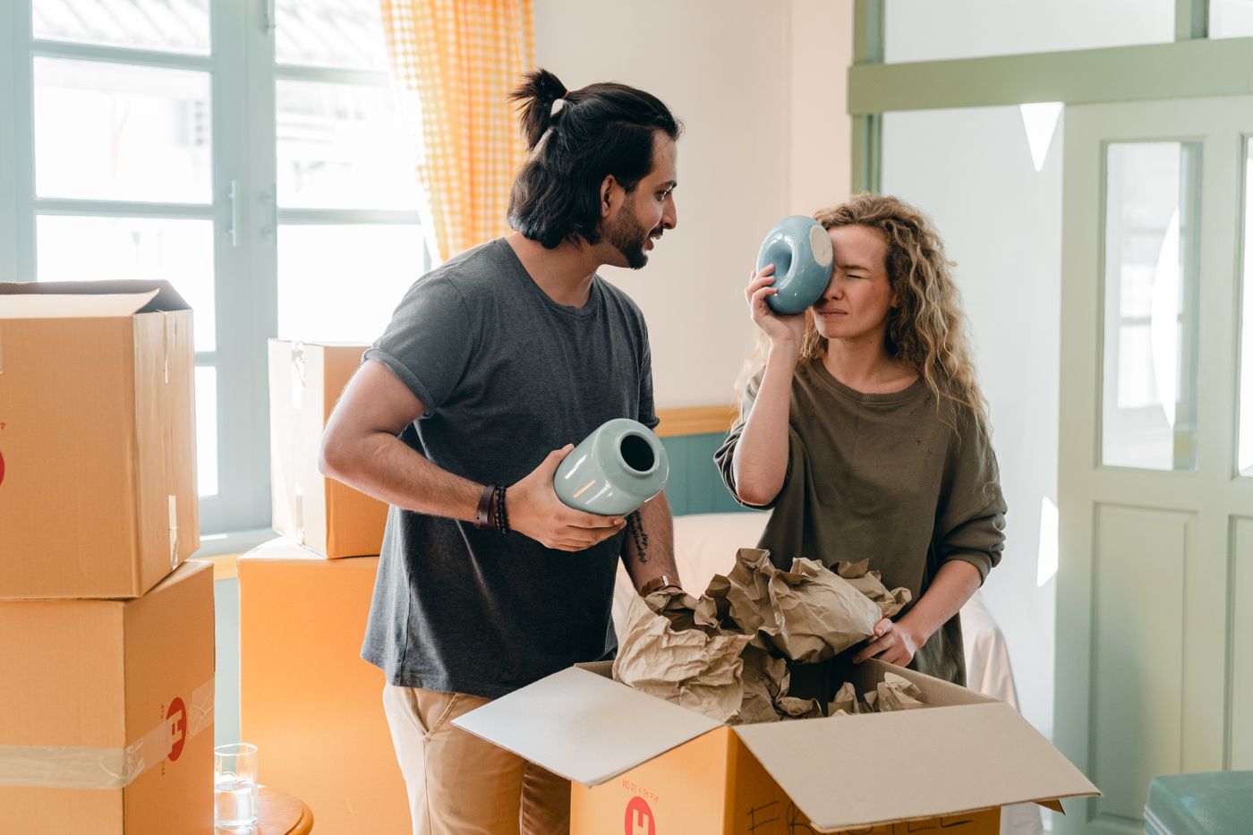 Couple packing household items into cardboard boxes in a living room